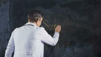 Male doctor writes Surgeon on the blackboard. video