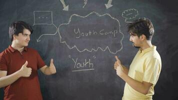Young man writing Youth Camp on blackboard. video