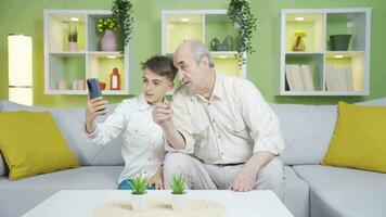 Grandfather and grandson making video calls with their parents.