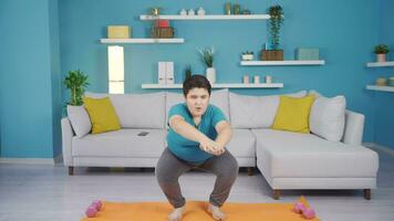 Obesity boy doing squat exercise at home. video