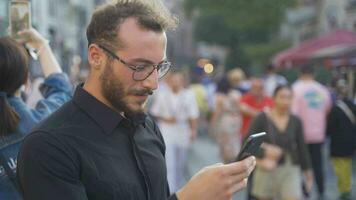 Young man using phone in crowd. video