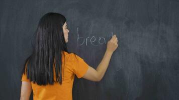Woman writing waste of bread on blackboard looks at camera with frustration. video