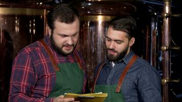 Two beer makers smiling to the camera, while working at their brewery video