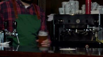 irreconhecível barman sorridente, colocando vidro do Cerveja em a contador video