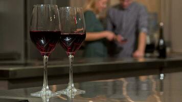 Wine glasses on the table, couple using smart phone together at home on the back video