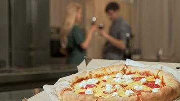 delicioso Pizza en el mesa, Pareja bebiendo vino juntos en el antecedentes video