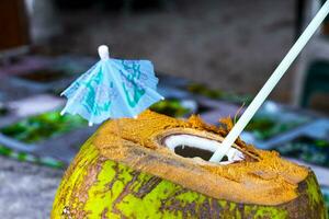 Coconut to drink with straw and small umbrella in Mexico. photo