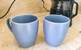 2 blue coffee cups and black coffee maker from Mexico. photo