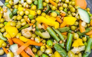 Vegetable dish with carrots peas onions beans on white plate. photo