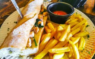 Baguette sandwich toast bread with chicken tomato salad potatoes fries. photo