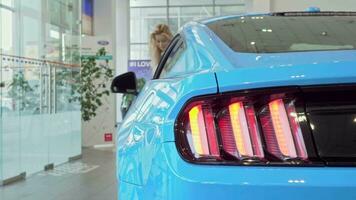 Selective focus on car lights, woman choosing automobile to buy on background video