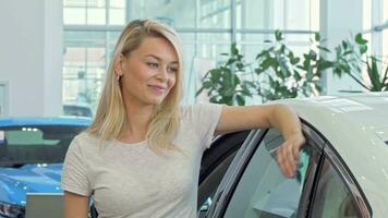 Happy beautiful female driver showing car keys to ker new automobile video