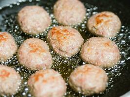 meatballs on a black pan with oil, close up photo