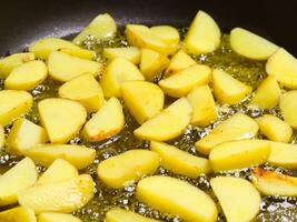 fried potatoes with hot oil in a pan, close - up photo