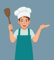 Young man in chef hat and apron holding ladle showing hand for copy space vector