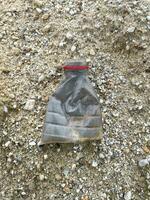 a plastic bottle filled with a garbage lies on the beach photo