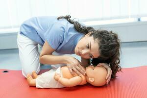 CPR practitioner examining airway passages on infant dummy. Model dummy lays on table and two doctors practice first aid. photo