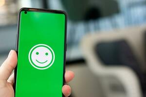 Woman holds a Smartphone with happy emoticons on the screen at a restaurant. concept of evaluating customer satisfaction at very good level of customer service photo