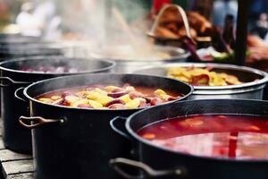 Beverages fruits and berries hot mulled wine in pots with steam in street food market. Generative AI photo