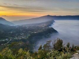 Sunrise view from Penanjakan 2 or Seruni point below as the mist still covers the sea of sand of Mount Bromo, East Java, Indonesia. Beautiful Nature background and wallpaper. photo