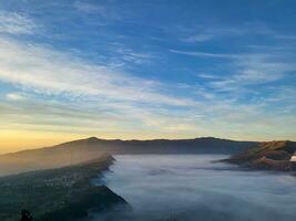 Sunrise view from Penanjakan 2 or Seruni point below can be seen as the fog begins to slowly shift to reveal a beautiful view of the sea of sand. photo