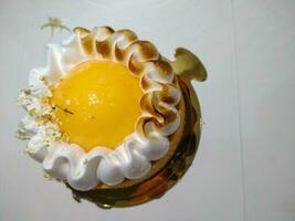 Lemon Meringue Pie made with shortcrust pastry, lemon curd and burnt Italian meringue. Served on a white table with minimal light. photo