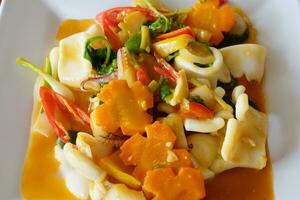 Delicious Stir Fried squid with salted egg yolk and carrot vegetable on white plate photo