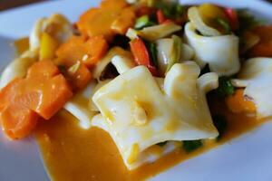 Delicious Stir Fried squid with salted egg yolk and carrot vegetable on white plate photo