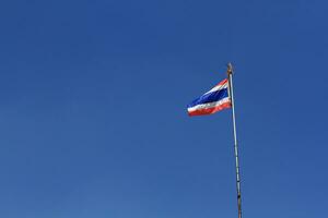 National Flag of Thailand is waving on pole with blue sky background photo