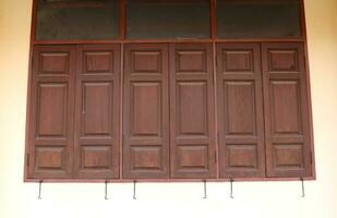 Dark brown rectangle shape closed wood window pattern on cement wall, Thailand. photo