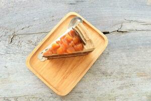 Top view of macadamia cake piece on rectangle shape wood plate on old and pale plank. photo