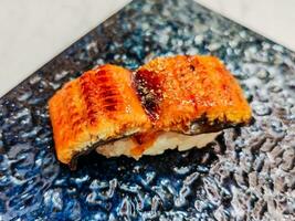 Eel rice sushi is on a plate ready to eat. Unagi Sushi is a popular type of sushi in Japanese cuisine. The eel is often cooked until it becomes tender and slightly crispy on the outside by grilling. photo