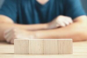 businessman sit on table and  wood empty four blocks with copy space for text or symbols, development concept for growth success process. photo