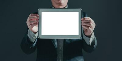 businessman in suit stand showing a tablet white screen display for mockup content. photo