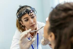 ENT clinic. Professional female doctor otorhinolaryngologist doing nose examination. Nasal congestion, sinusitis, allergy concept. Otolaryngologist examines woman's nose with nasal dilator. photo