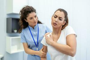 mujer médico osteópata en médico uniforme fijación mujer pacientes hombro y espalda articulaciones en manual terapia clínica durante visita. profesional osteópata durante trabajo con paciente concepto foto