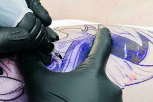 profesional tatuaje artista hace un tatuaje en el masculino pierna foto