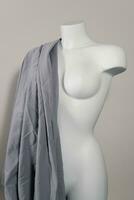 White modern mannequin or dressmakers dummy with gray fabric and hanging measuring tape photo