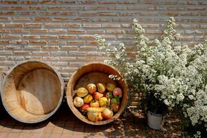 floreciente blanco flores en florero y frutas en madera cesta decorativo para Clásico ladrillo pared foto