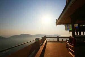 Mañana de luz de sol y terraza punto de vista de patrimonio dorado templo y naga en poste de luz situado en el montaña en el del Norte de Tailandia foto