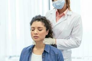 endocrinólogo examinando garganta de joven mujer en clínica. mujer con tiroides glándula prueba . endocrinología, hormonas y tratamiento. inflamación de el dolorido garganta foto