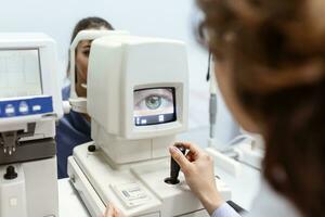 médico pruebas para ojos con especial óptico aparato en moderno clínica. oftalmólogo examinando ojos de un paciente utilizando digital microscopio durante un médico examen en el oftalmológico oficina foto