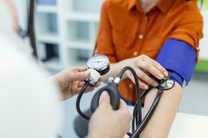 Doctor using sphygmomanometer with stethoscope checking blood pressure to a patient in the hospital. photo