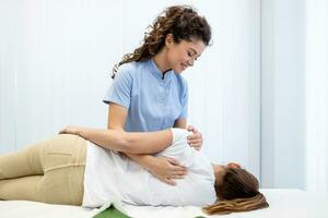 Close up of female osteopath doing shoulder blade therapy on young woman. photo