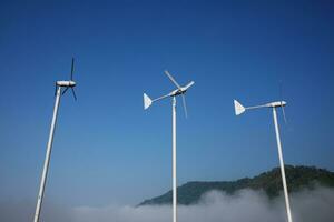 Vintage Windmills airplane shape for electric power production with foggy and blue sky on the hill and mountain photo