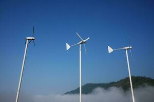 Vintage Windmills airplane shape for electric power production with foggy and blue sky on the hill and mountain photo