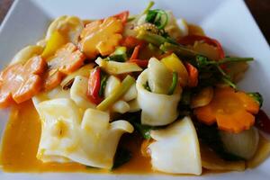 Delicious Stir Fried squid with salted egg yolk and carrot vegetable on white plate photo