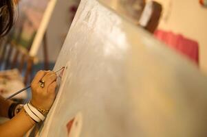 Close-up artist's hands works on painting on canvas, in creative art workshop, holds a palette with oil paints and brush photo