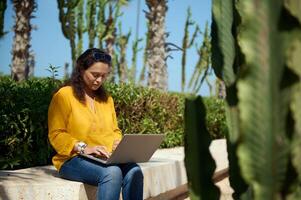 Confident portrait of a purposeful female developer, programmer, freelance entrepreneur typing text on laptop keyboard photo