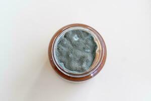 Open jar with sweet jam and mold on a white background. photo